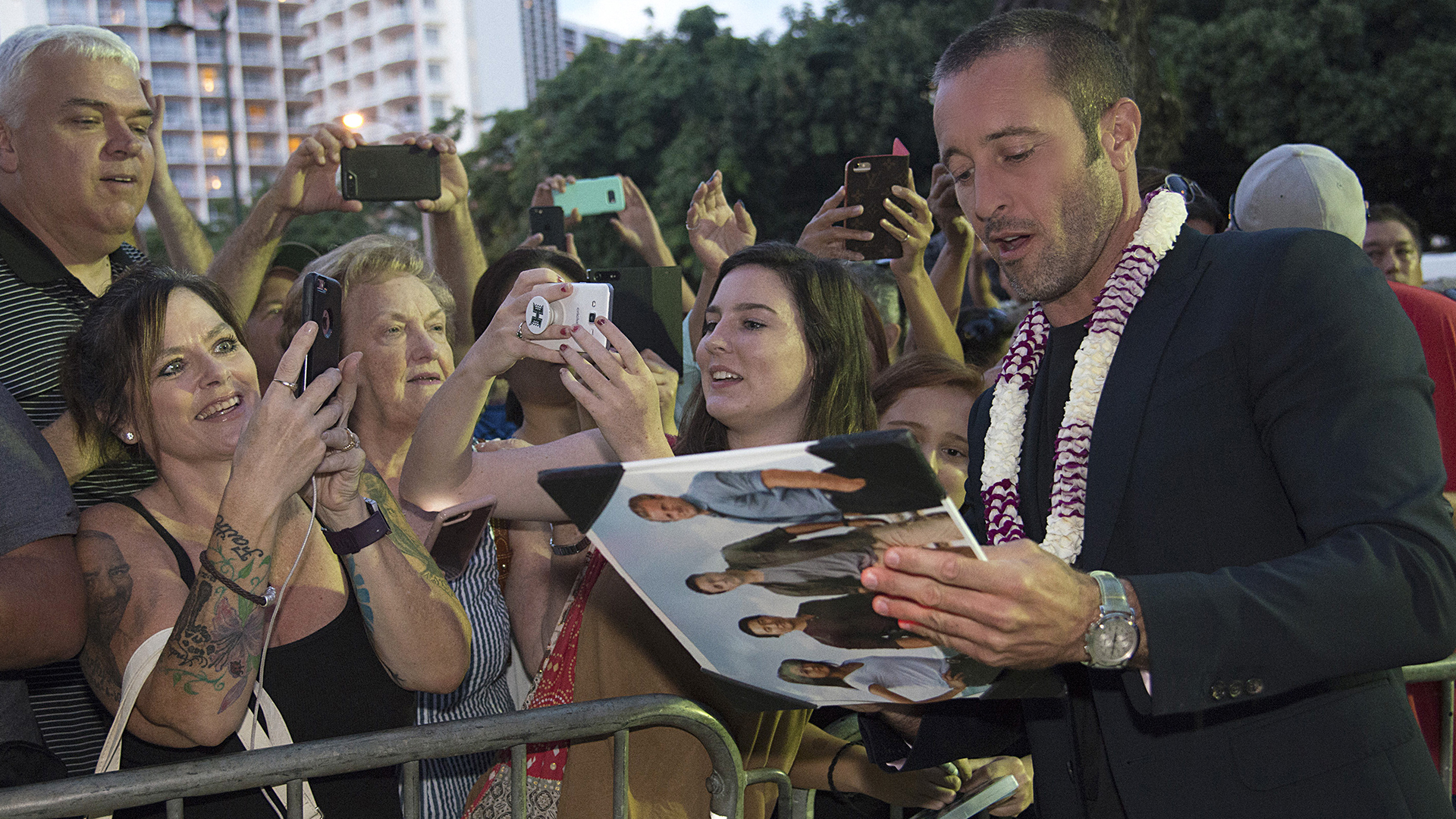 Alex O'Loughlin autographs show art for fans while walking the red carpet.